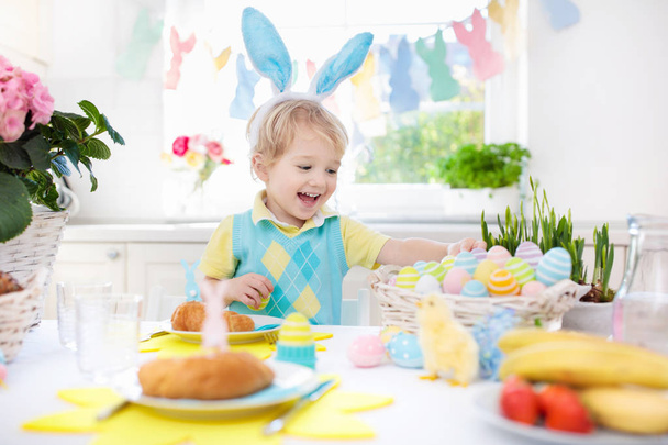 Crianças no pequeno-almoço da Páscoa. Cesta de ovos, orelhas de coelho
. - Foto, Imagem
