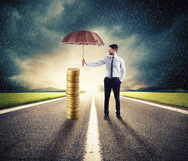 Empresário protege suas economias de dinheiro com guarda-chuva. conceito de seguro e proteção de dinheiro
 - Foto, Imagem