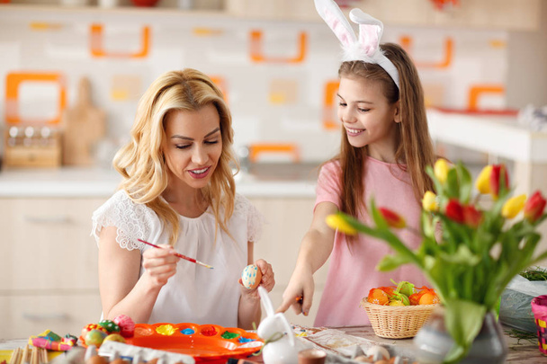 Female child with young mother coloring Easter eggs - Foto, Bild
