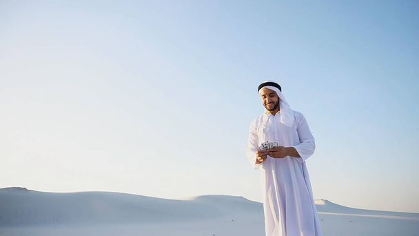 Ευτυχισμένος άνθρωπος μουσουλμανικές φαίνεται μέσω των τραπεζογραμματίων και εκτός από τον εαυτό του με - Φωτογραφία, εικόνα
