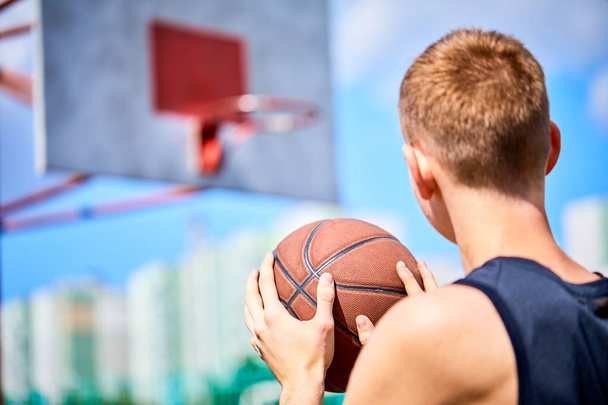 человек держит мяч во время игры в баскетбол на открытом воздухе
 - Фото, изображение