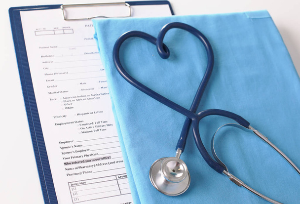 een stethoscoop vormgeving een hart op een medische uniforme, close-up - Foto, afbeelding