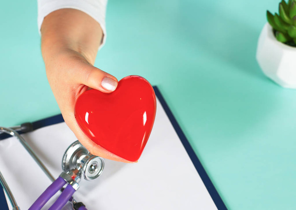 Женщина-врач со стетоскопом, держащая сердце - Фото, изображение