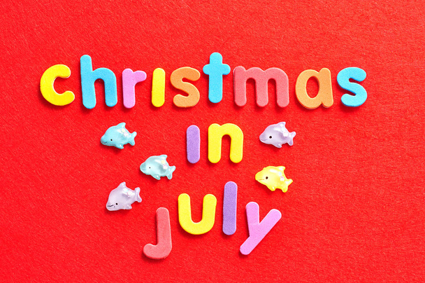 Sanat joulu heinäkuussa värikkäillä kirjaimilla punaisella taustalla ja delfiinit hahmoja
 - Valokuva, kuva