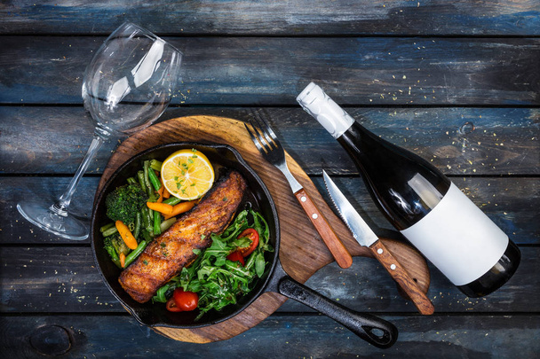 Grilled salmon fillet in a frying pan, vegetables, arugula with a lemon. - Foto, immagini