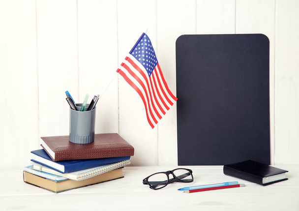 Books, notebooks, glasses and the US flag on the desk. English language learning. Flag the United States of America. - Photo, image