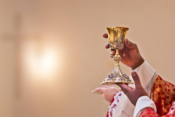 las manos del sacerdote levantan la sangre de Cristo
 - Foto, Imagen