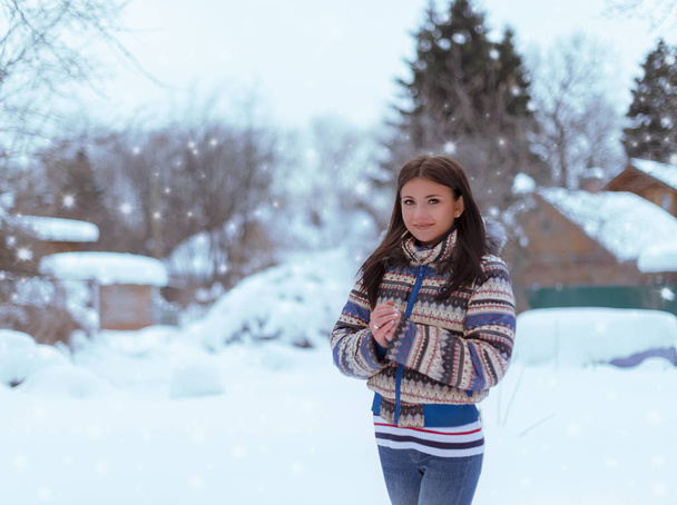 Μια όμορφη νεαρή κοπέλα στέκεται στο φόντο της ένα χειμερινό τοπίο υπαίθρου - Φωτογραφία, εικόνα