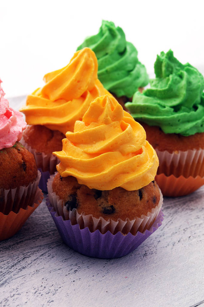 leckere Cupcakes auf Holzuntergrund. Geburtstagskuchen im Regenbogen - Foto, Bild