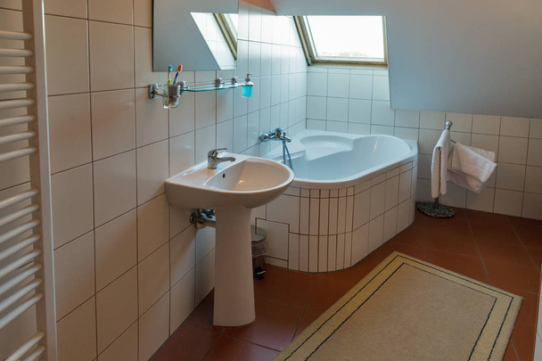 Moderne badkamer met hoekbad, lavabo en venster. - Foto, afbeelding