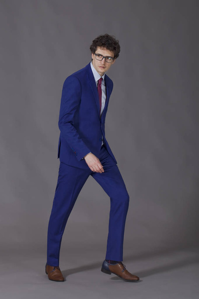 Curly man with glasses wearing in blue suit making step - Foto, Imagen
