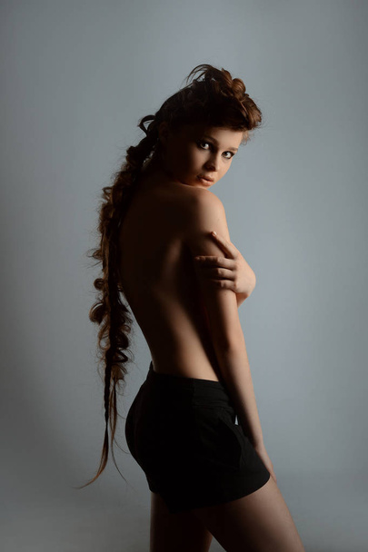 a girl in a skirt with bare back in the Studio on gray background - Foto, afbeelding