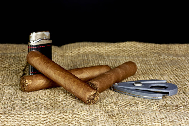 Cuban cigars with a cutter and a lighter on a black background - Photo, Image
