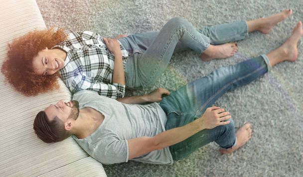 smiling couple lying on a carpet in a new apartment - 写真・画像