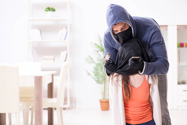 Озброєний чоловік нападає на молоду жінку вдома
 - Фото, зображення