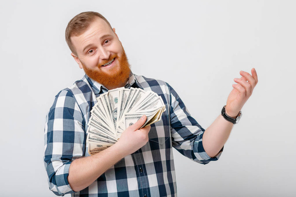 man with beard holding lot of hundred-dollar bills - Foto, afbeelding