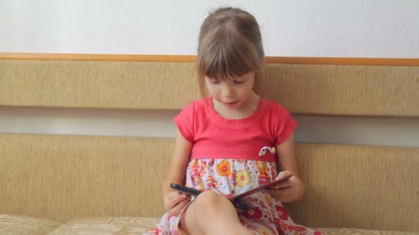Pieni tyttö lukee e-kirjaa sohvalla
 - Materiaali, video