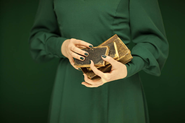 beautiful woman figure in dark green 50's dress holding vintage book, hands with green nail polish - Fotó, kép