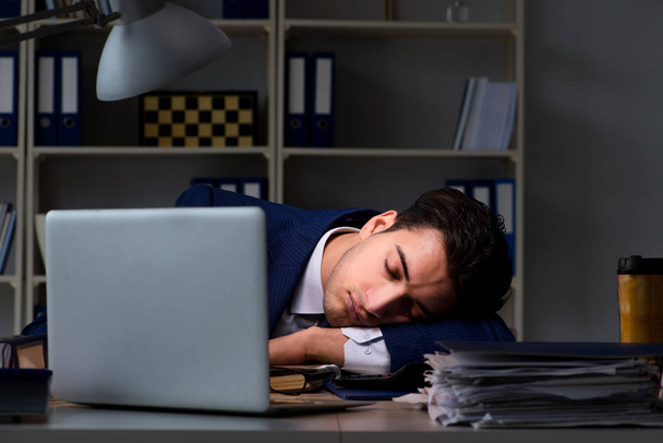 Biznesmen, zmęczony i śpiący w biurze po godzinach nadliczbowych godzin - Zdjęcie, obraz