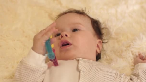 体内の赤ちゃんベビーベッドで仰向けし、彼の手でおもちゃを保持. - 映像、動画