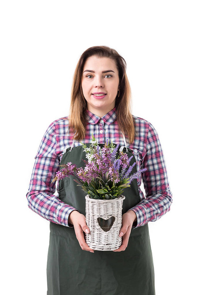 portrait of smiling woman professional gardener or florist in apron holding flowers in a pot isolated on white background - Foto, immagini