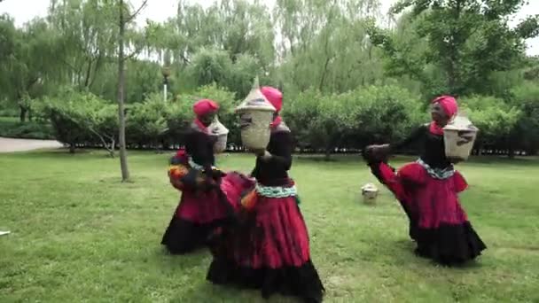 Three african women dancing a folk dance in traditional costumes with baskets - Footage, Video