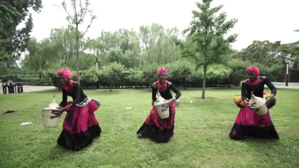 Three african women dancing a folk dance in traditional costumes with baskets - Footage, Video