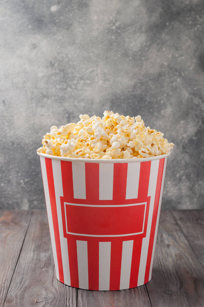 Popcorn elszigetelt szürke csíkos vödörben (vörös és fehér doboz) - Fotó, kép