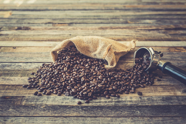 Смажені кавові зерна в мішку на дерев'яному фоні
 - Фото, зображення