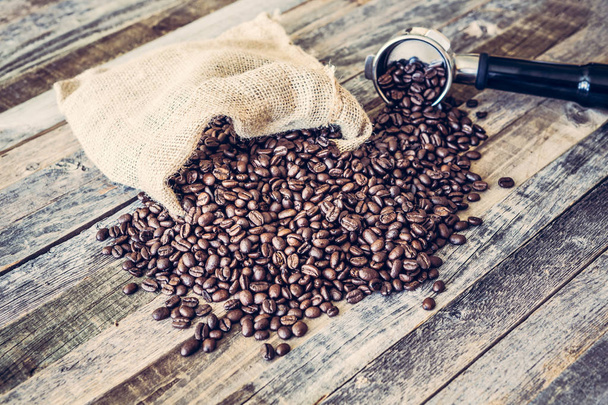 Roasted coffee beans in a bag on wooden background - Photo, Image