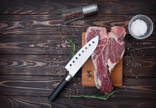 Raw meat steak on dark wooden background ready to roasting - Photo, image