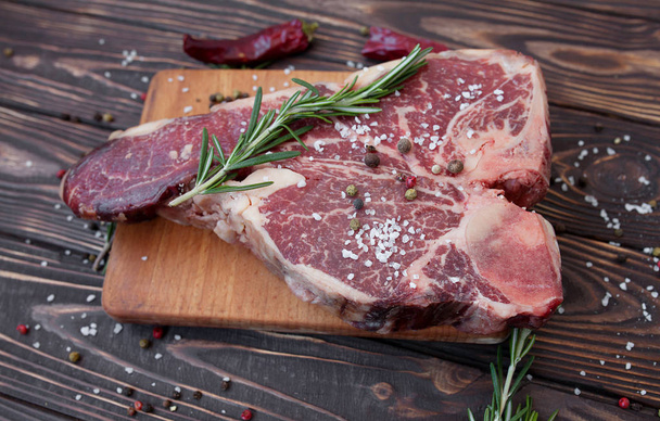 Raw meat steak on dark wooden background ready to roasting - Photo, Image