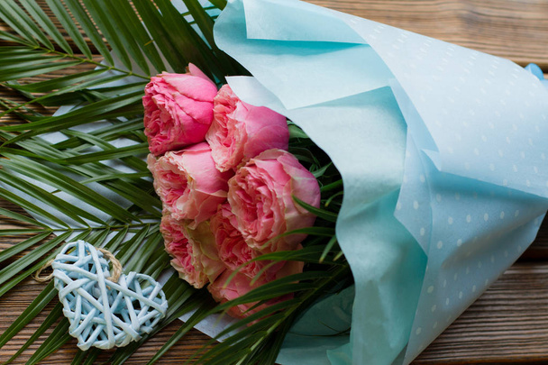 ποιον σε σχήμα τριαντάφυλλο σε μπλε πακέτο με την καρδιά σε ξύλινο bacckground - Φωτογραφία, εικόνα