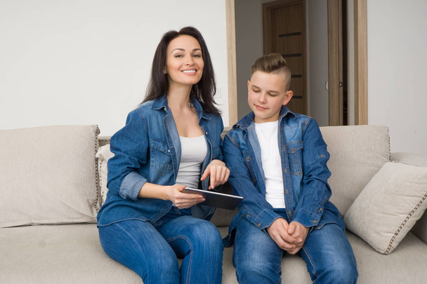 Happy family sitting on sofa and using digital tablet at home - Φωτογραφία, εικόνα