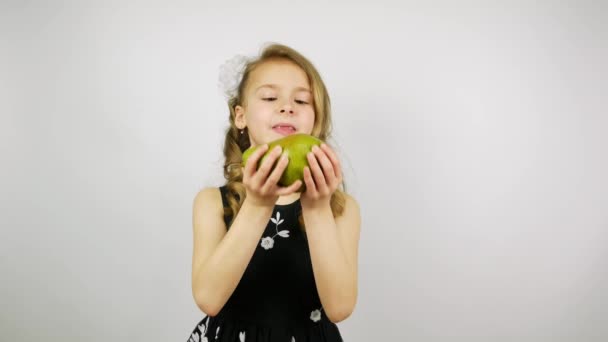 Chica rubia en un hermoso vestido comiendo una pera sobre un fondo blanco
. - Imágenes, Vídeo