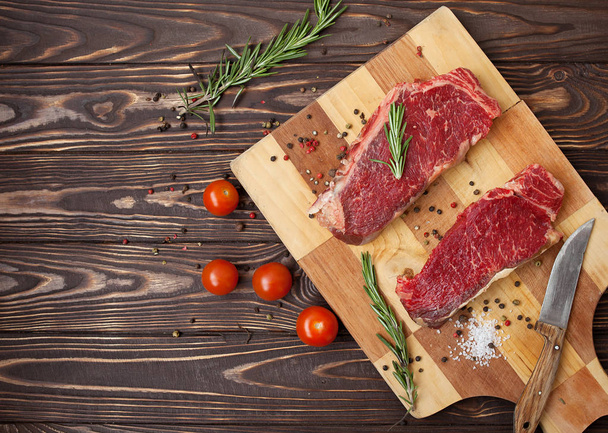 Raw beef steak on a dark wooden table. - Фото, зображення