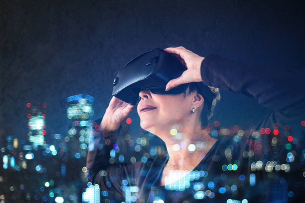 An elderly woman in virtual reality glasses. An elderly person using modern technology. - Foto, Bild