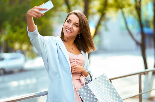 Selfie time. Woman in shopping. Happy woman with shopping bags enjoying time. Consumerism, shopping, lifestyle concept. woman holding shopping bags on the street with copy space - Фото, зображення