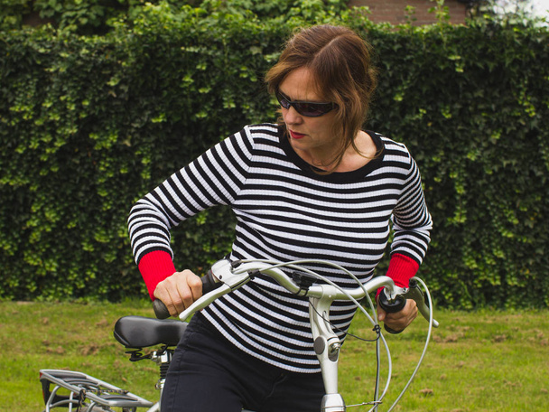 Σύγχρονη ζωτικής σημασίας γυναίκα ποδηλάτης με τιγρέ πουλόβερ. - Φωτογραφία, εικόνα