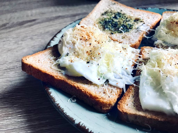 Νόστιμο αγγλικό πρωινό αποτελείται από τοστ με βότανα και ποσέ αυγά Benedict με παρμεζάνα και πιπέρι - Φωτογραφία, εικόνα