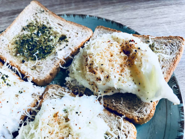 Sabroso desayuno inglés hecho de pan tostado con hierbas y huevos de Benedicto escalfados con queso parmesano y pimienta
 - Foto, imagen