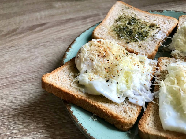 Sabroso desayuno inglés hecho de pan tostado con hierbas y huevos de Benedicto escalfados con queso parmesano y pimienta
 - Foto, Imagen