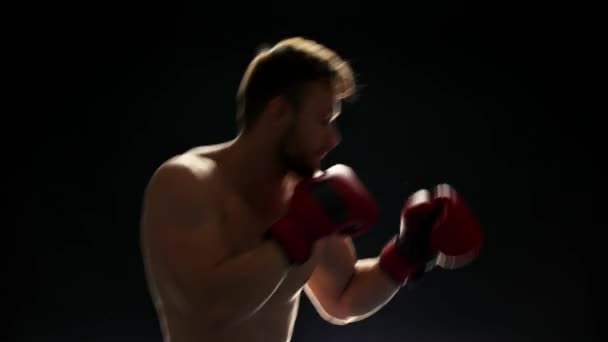 Молодой боксёр тренируется на тёмном фоне
. - Кадры, видео
