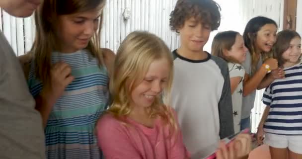 Duża grupa młodych chłopców i dziewcząt udostępnianie tabletów i telefonów inteligentnych technologii - Materiał filmowy, wideo