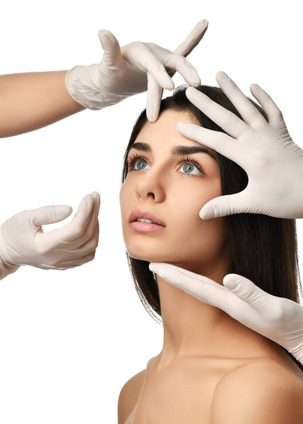 Orvos kezét orvosi kesztyűk touch gyönyörű fiatal nő csukott szemmel arc plasztikai műtét után  - Fotó, kép