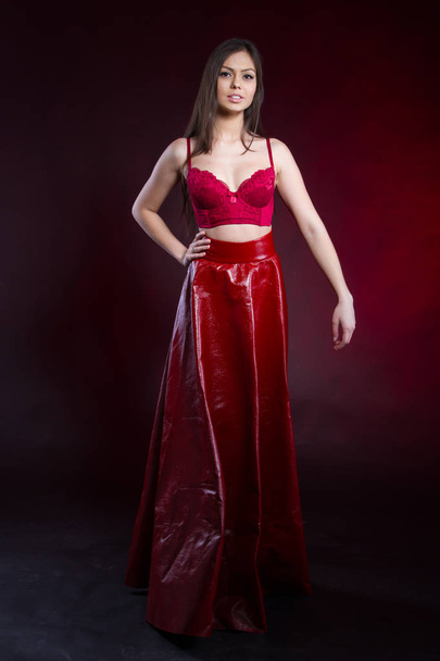Emotional young girl in a leather skirt and a red lace bra. Studio portrait - Foto, Imagem