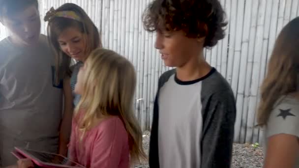 Groupe de jeunes amis regardant une tablette numérique ensemble souriant et parlant
 - Séquence, vidéo