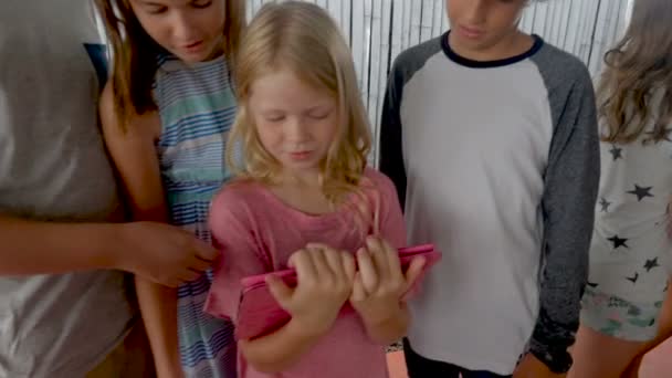 Szczęśliwy zróżnicowaną grupę młodych chłopców i dziewcząt patrząc cyfrowych tabletki razem - Materiał filmowy, wideo