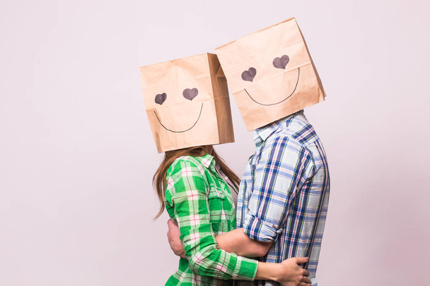 Amor casal cobrindo seus rostos com saco de papel sobre fundo branco
 - Foto, Imagem