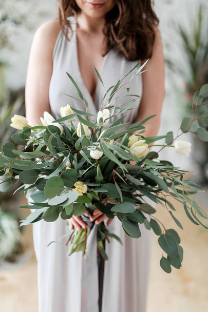 Lush bouquet of eucalyptus and tulips in the hands of the bride - Photo, Image